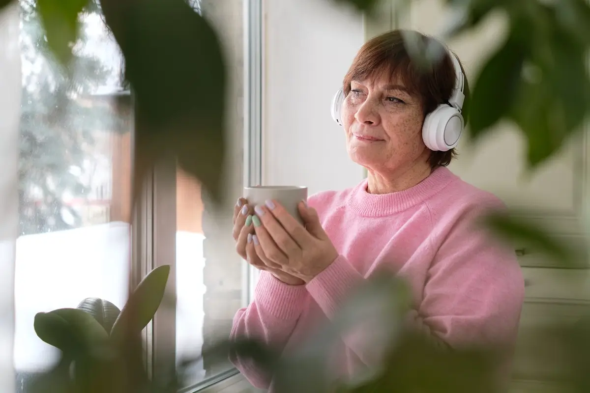 senior-woman-in-pink-savoring-coffee-and-music-by-2023-06-09-22-20-43-utc.webp